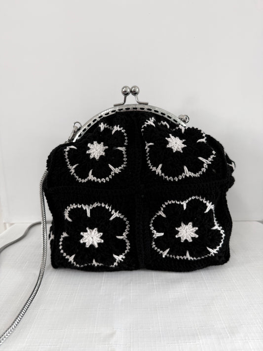 Black handmade crochet kiss lock handbag with white floral granny square design and silver chain strap