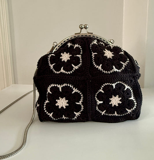 Black handmade crochet kiss lock handbag with white floral granny square design and silver chain strap