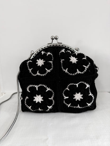 Black handmade crochet kiss lock handbag with white floral granny square design and silver chain strap