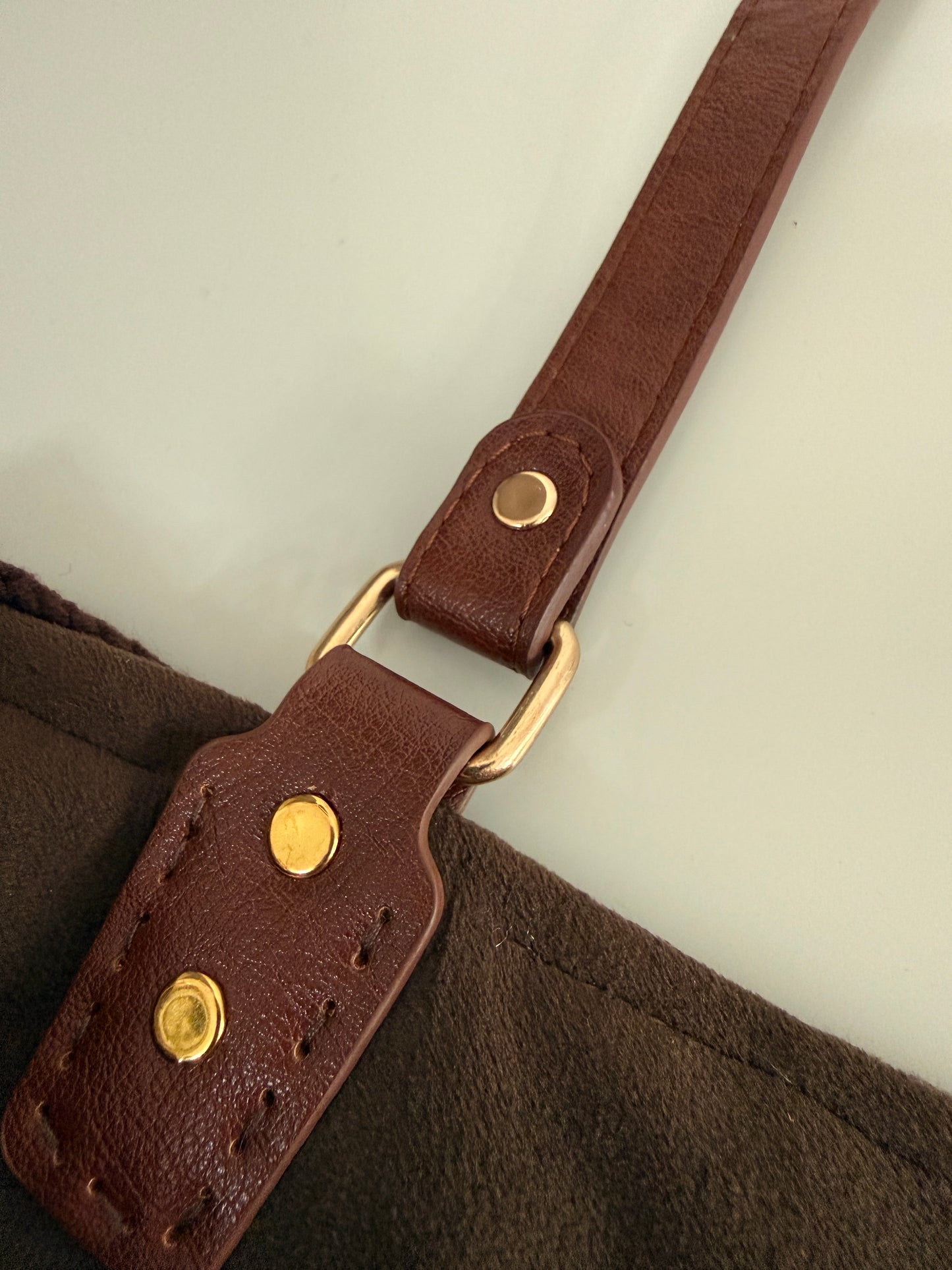 Close up of brown strap, gold hardware and handmade crochet bag construction