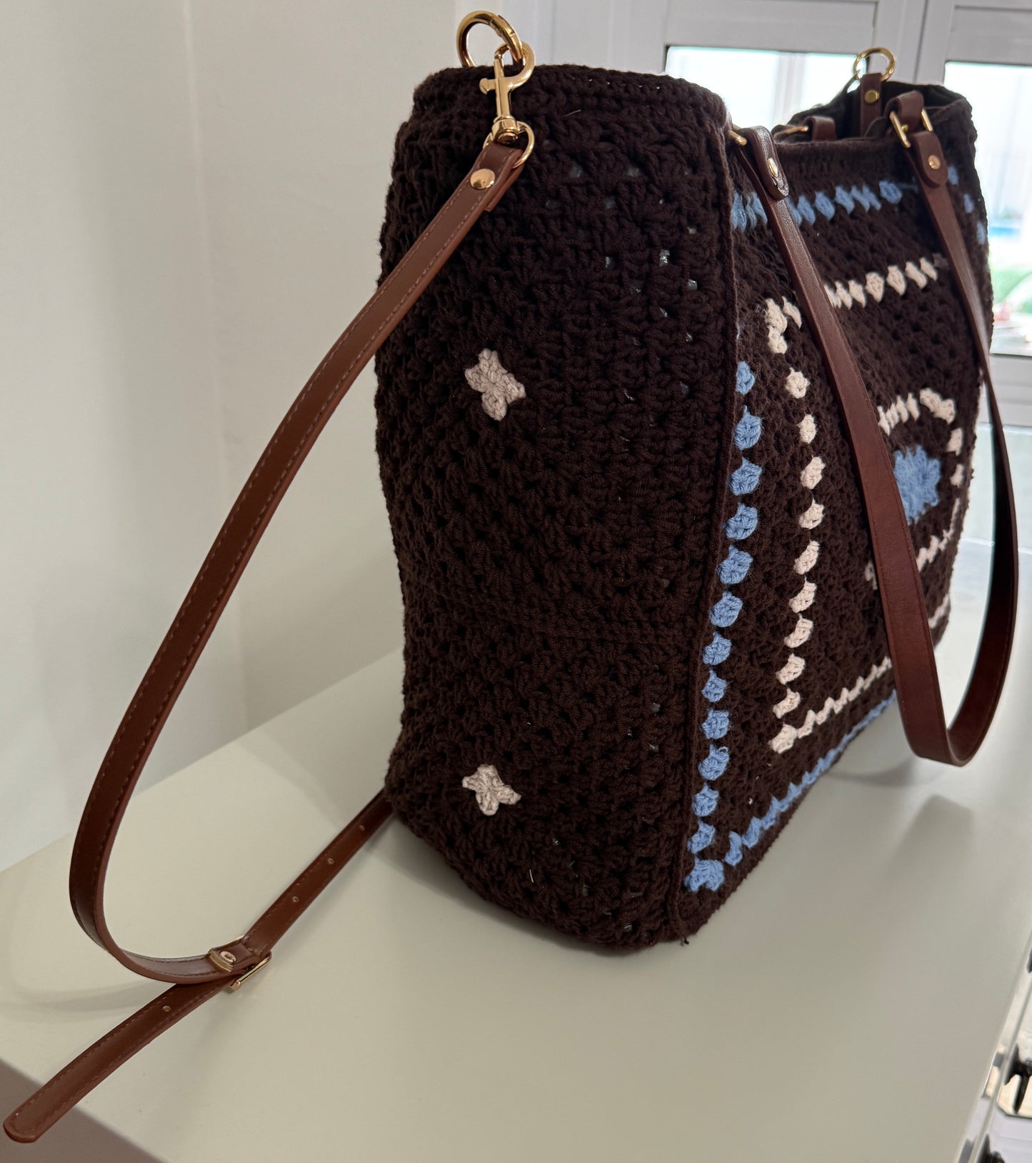 Carryall Large crochet tote bag shown on model with brown handles and blue granny stitch detail