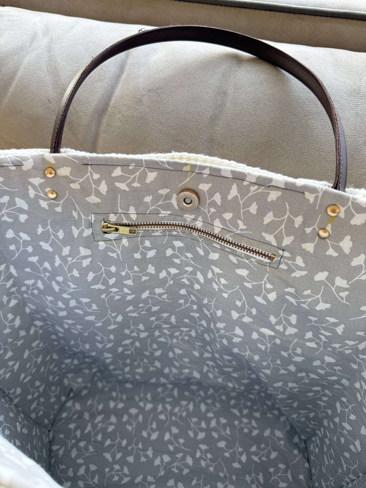 Interior zip pocket, magnetic closure and grey floral lining inside large handmade crochet tote bag