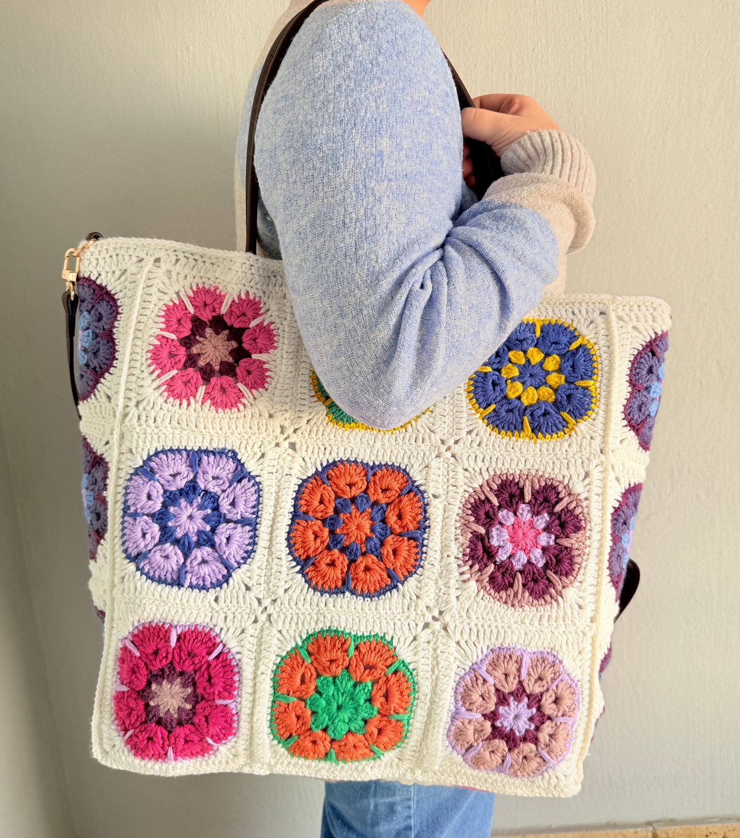 Handmade large crochet tote bag worn on the shoulder with colourful floral granny square design