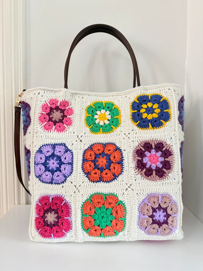 Large handmade granny square crochet tote bag with cream base, colourful floral design and brown handles