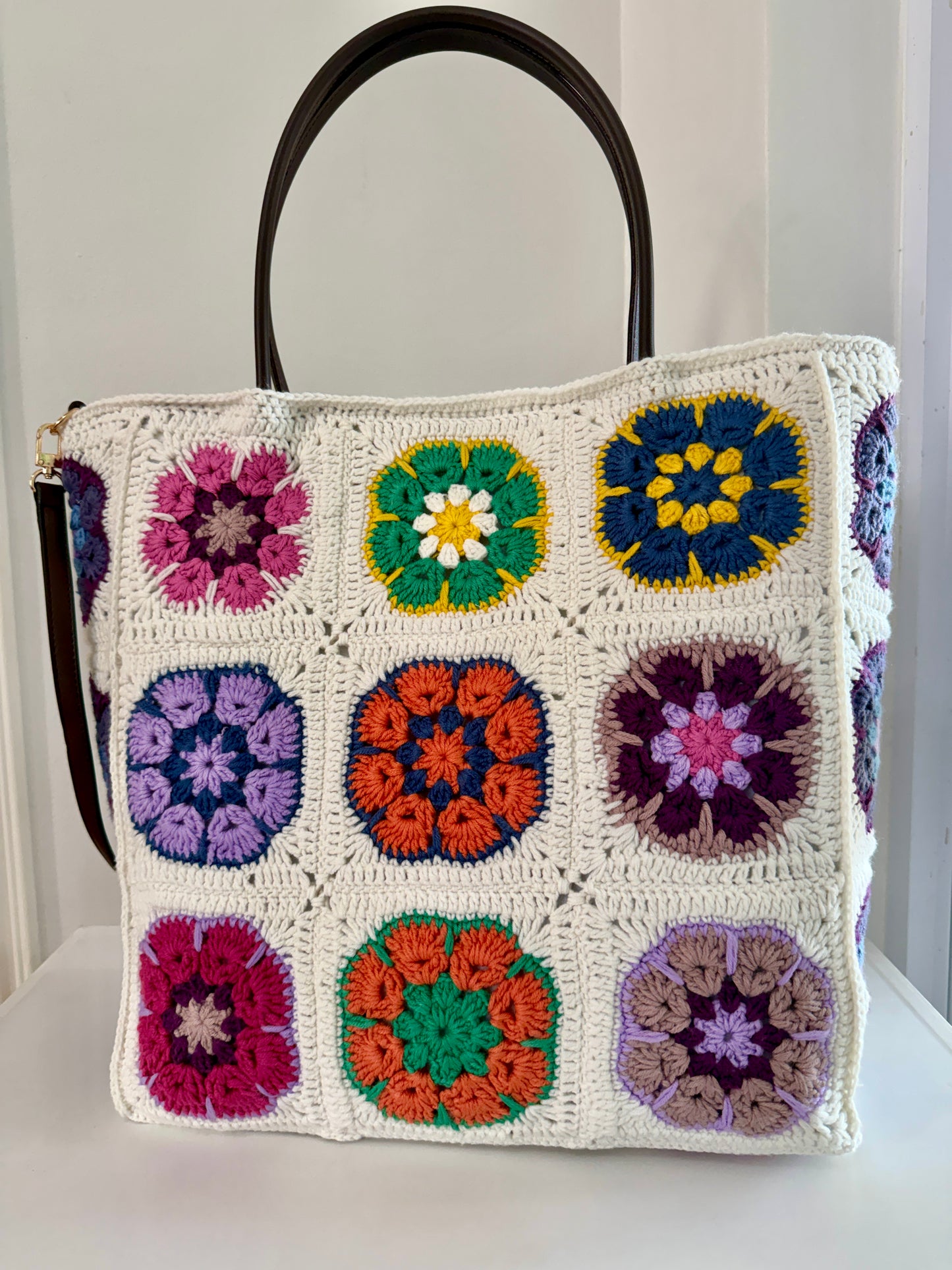 Cream granny square crochet tote bag with brown handles and colourful handmade floral motifs