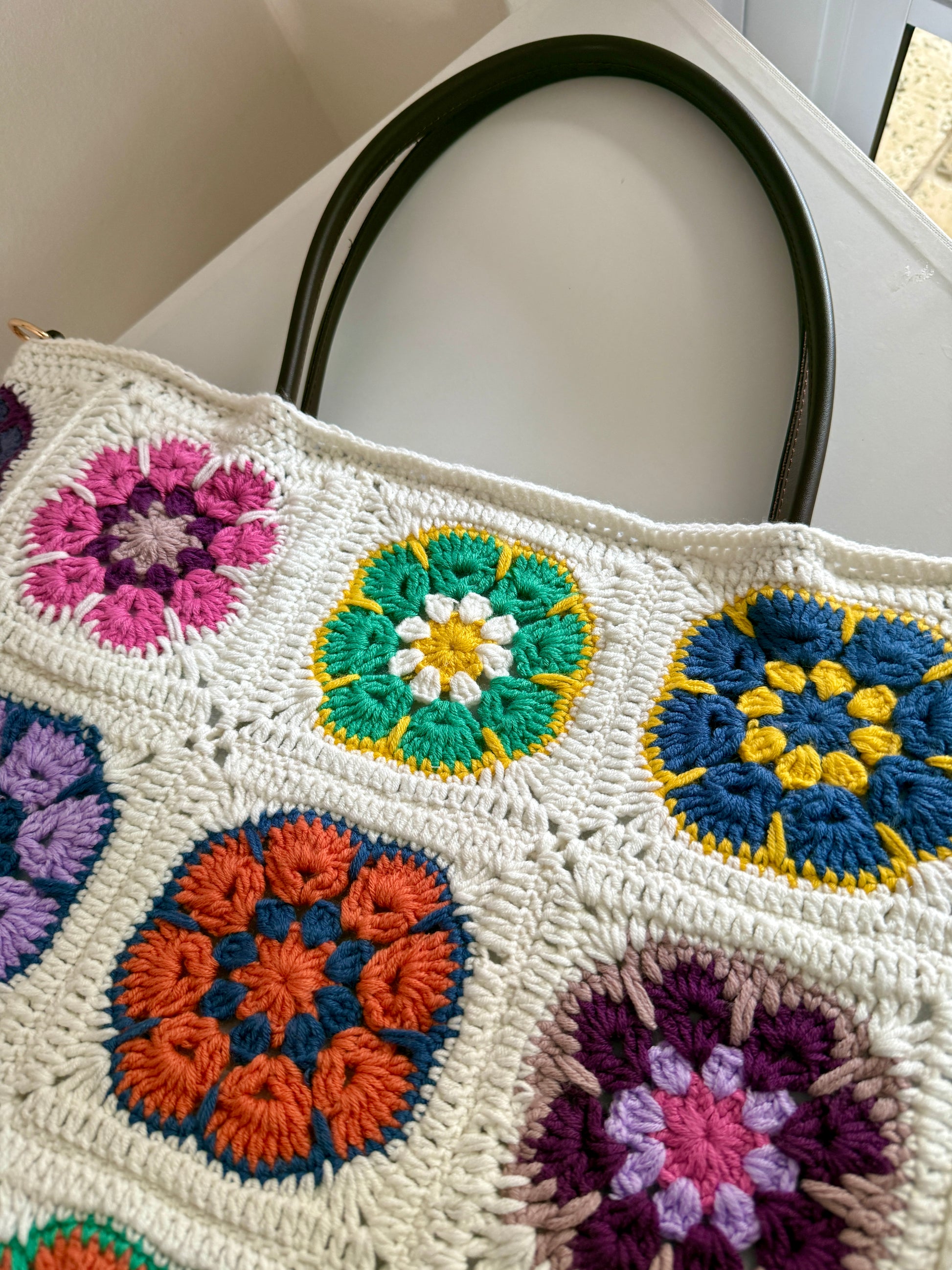 Close up of colourful floral granny square crochet texture on handmade cream tote bag