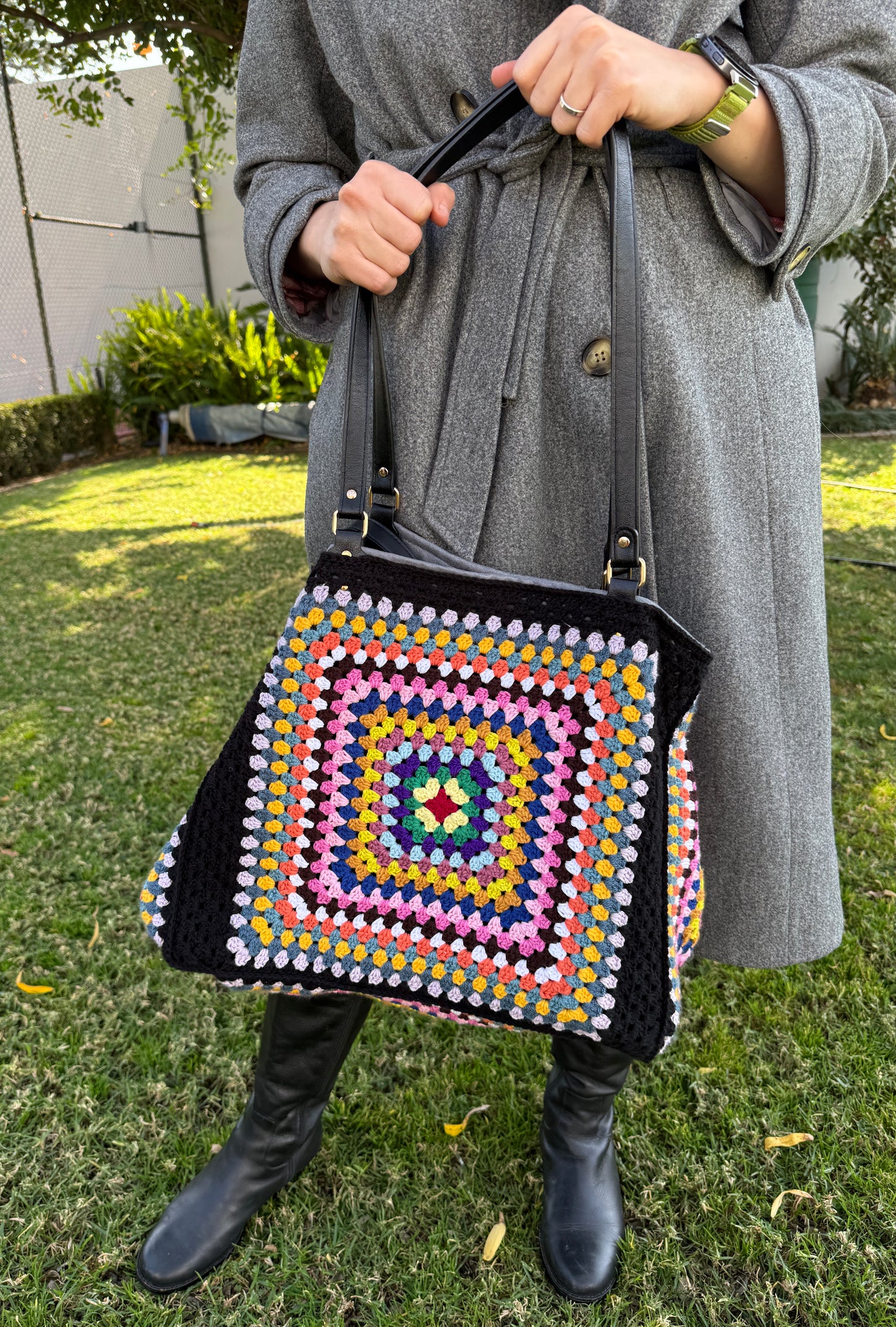 Person holding a colorful crochet bag outdoors