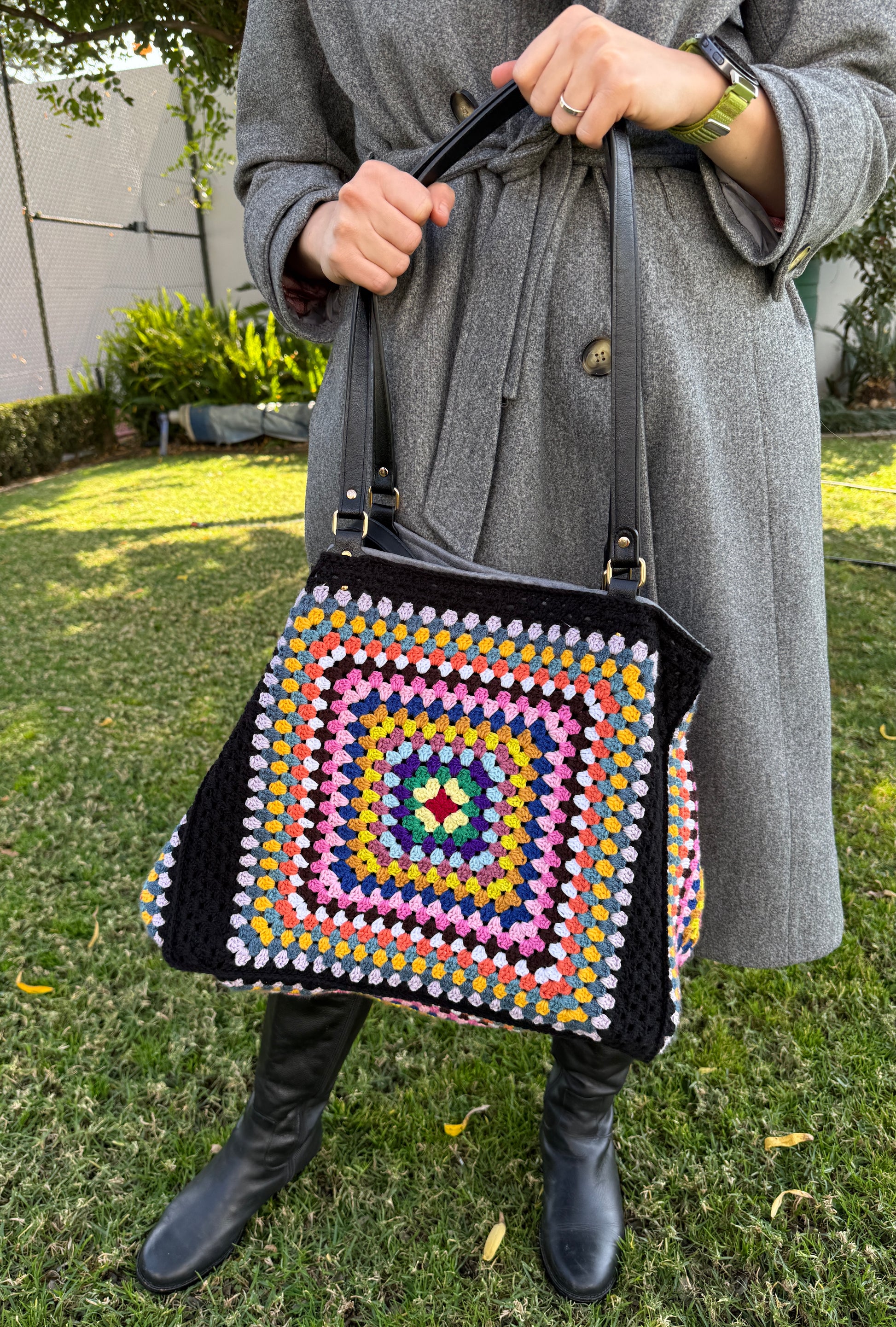 Person holding a colorful crochet bag outdoors