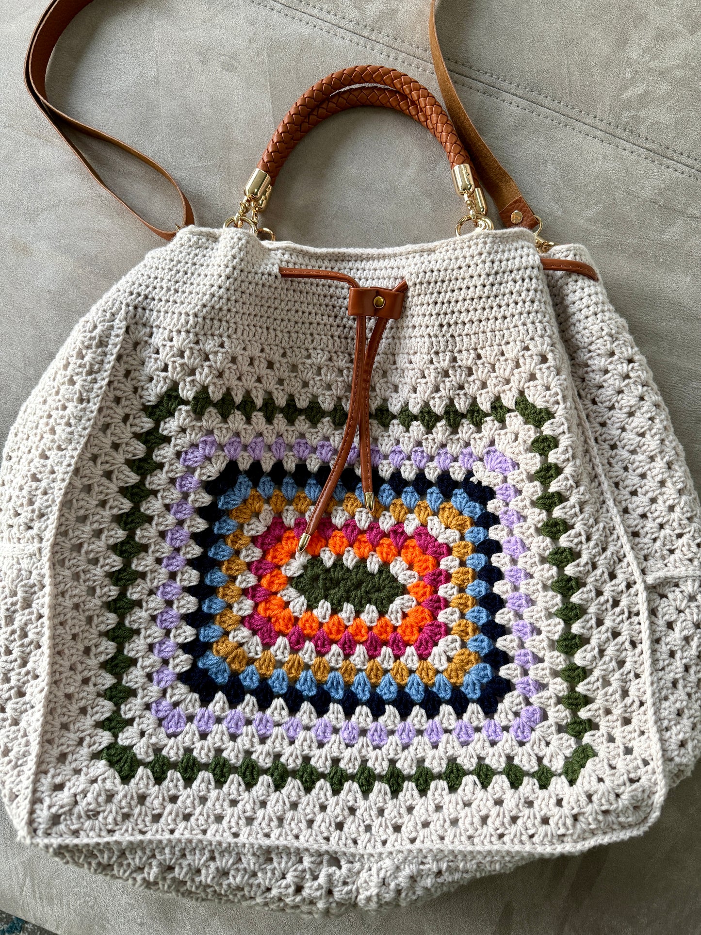 Crocheted bag with a colorful square pattern on a neutral background