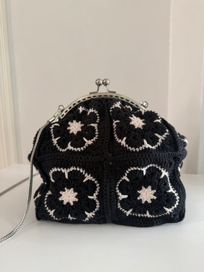 Black crochet kiss lock shoulder bag worn with detachable silver chain strap