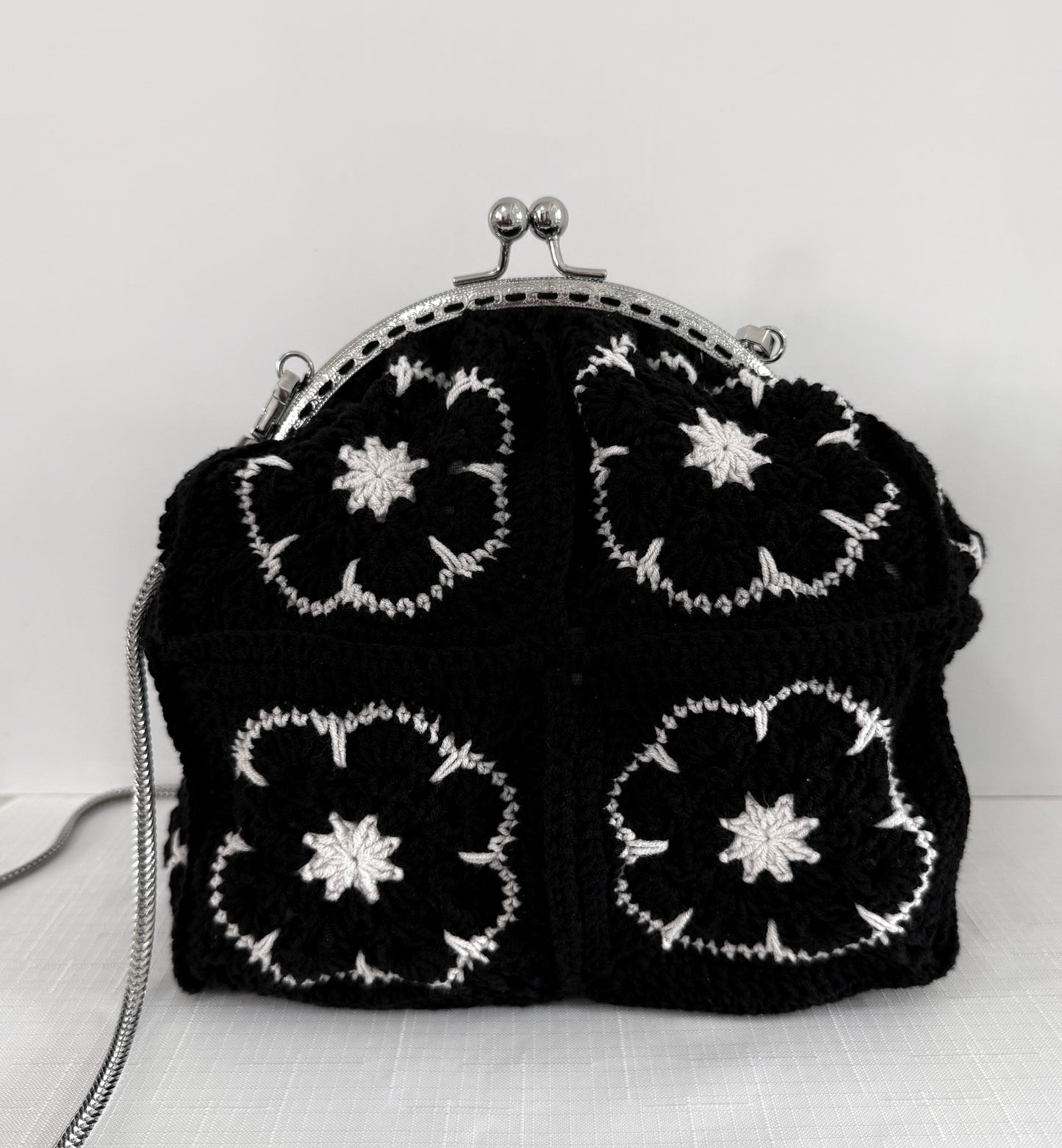 Close up of black and white floral granny square crochet design on handmade handbag