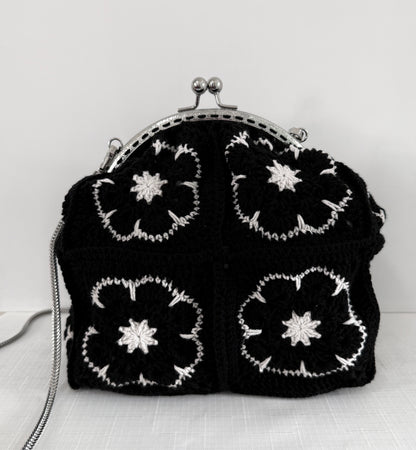 Close up of black and white floral granny square crochet design on handmade handbag