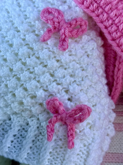 Close-up of pink crochet bow details on the handmade bunny’s white crochet dress.