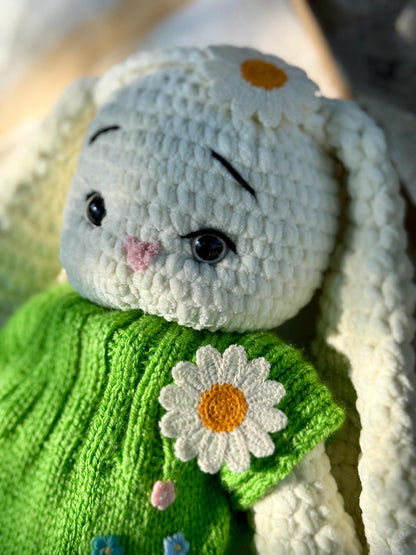 Close-up of cute crochet bunny in a green floral embroidered dress with daisy detail.