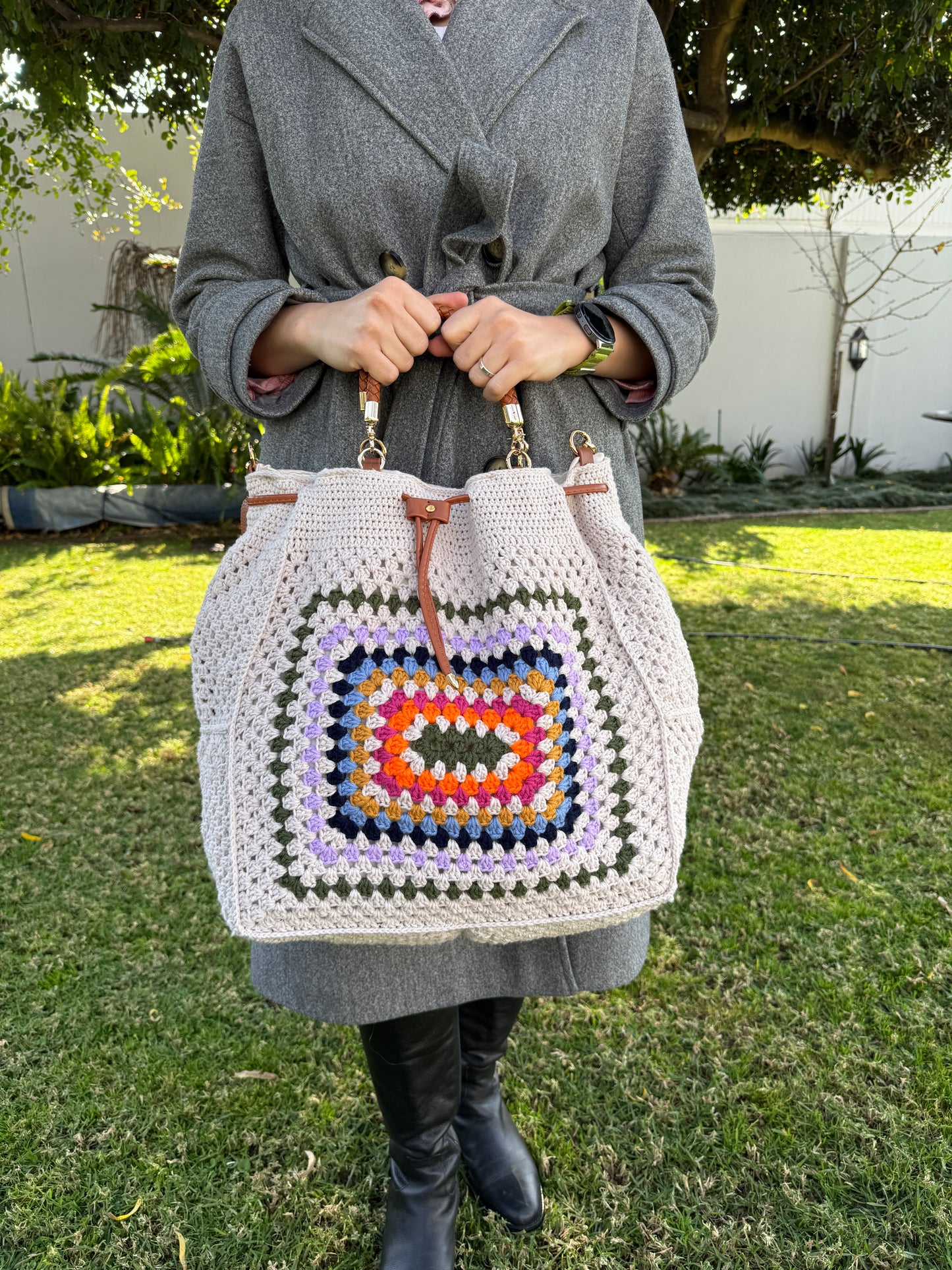 Person holding a colorful crocheted bag outdoors